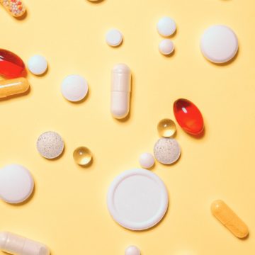 Lääketabletteja ja pillereitä keltaisella taustalla.